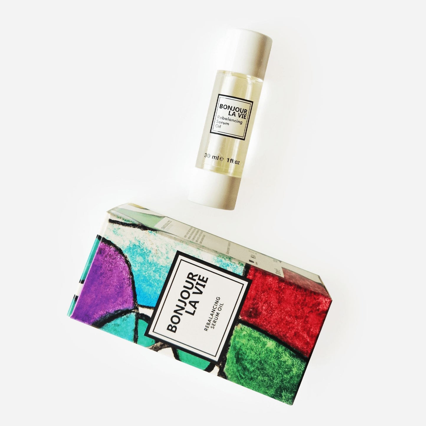 Immagine su fondo bianco del flacone e della scatola colorato con toni porpora, azzurro, verde e rosso di Rebalancing Serum da 30 ml di Bonjour La Vie