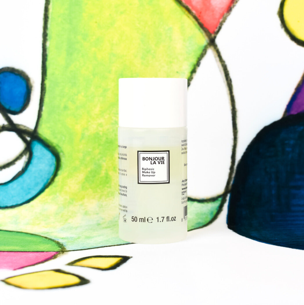 Image of the bottle of the biphasic makeup remover and part the Luca Maraldi paiting on the background, gree, blue and white. Immagine del flacone di struccante bifasico con dettaglio della tela di Luca Maraldi sullo sfondo, nei toni del verde, blu e bianco