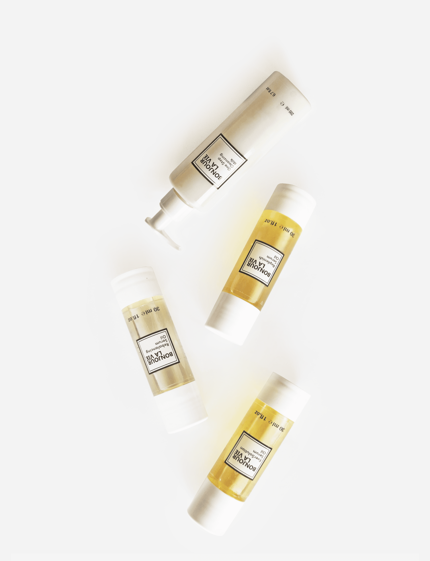 Immagine su fondo bianco dei quattro prodotti di Bonjour La Vie capovolti One Step Cleansing Milk, EverSolution Serum Oil, Replenish Serum Oil, Rebalancing Serum Oil